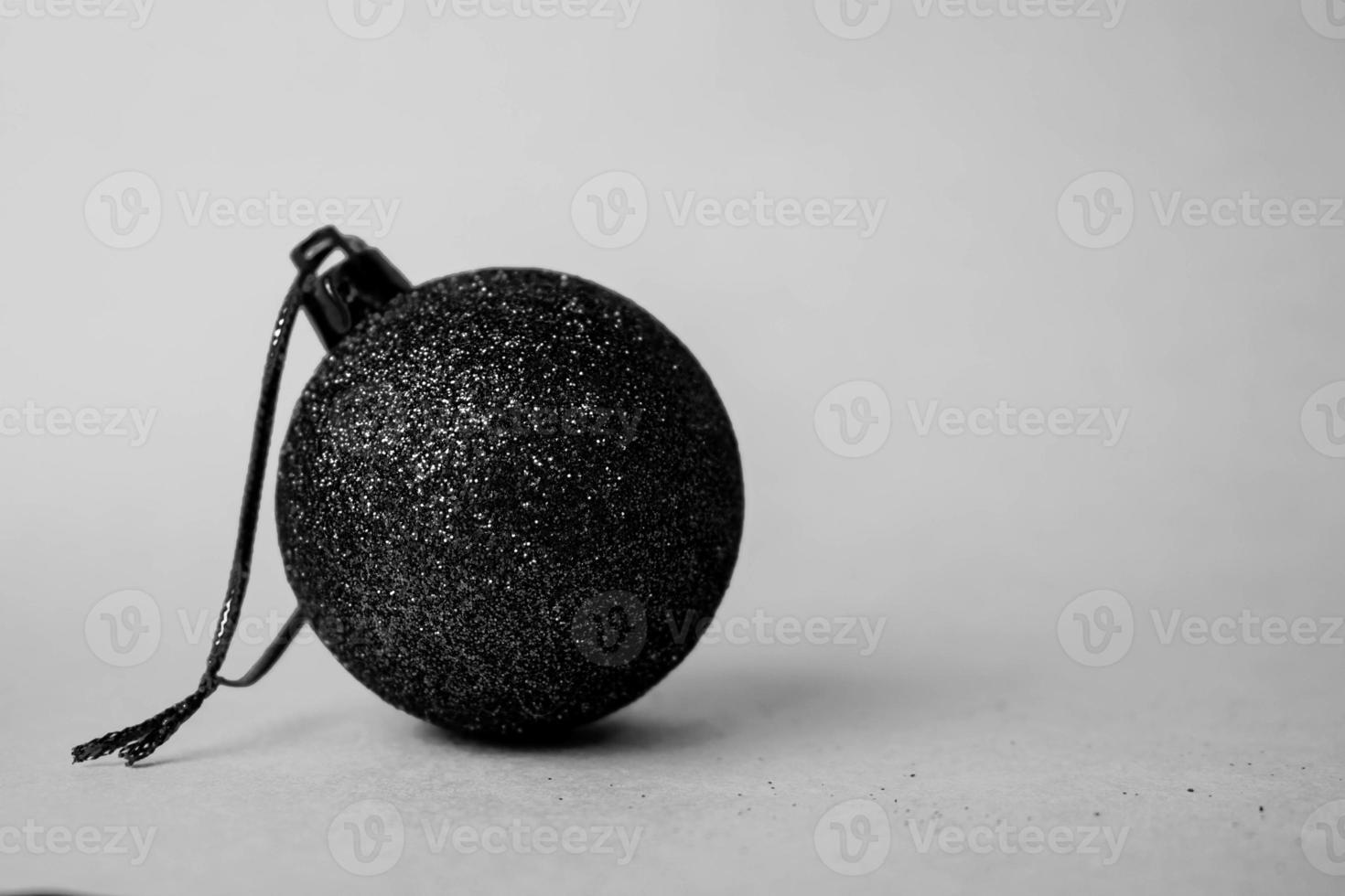 Small round glass plastic winter elegant shiny decorative beautiful xmas festive Christmas ball, Christmas toy plastered over sparkles on a black and white background photo