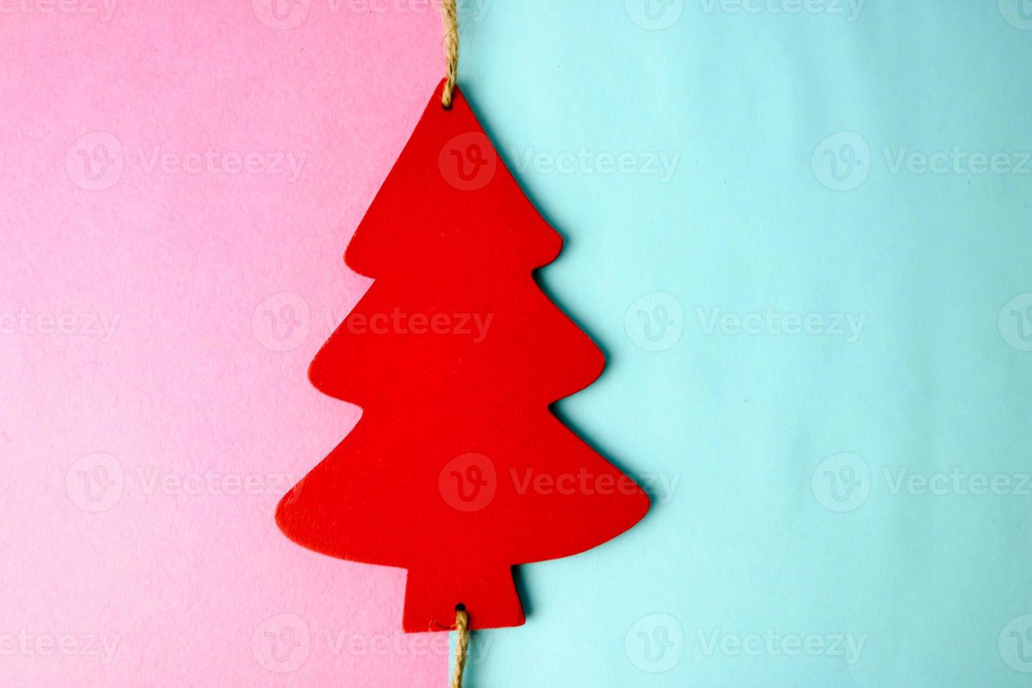 Festive New Year's Christmas beautiful bright multi-colored joyful blue and pink background with a small toy wooden red and white cute Christmas tree. Flat lay. Top view. Holiday decorations photo