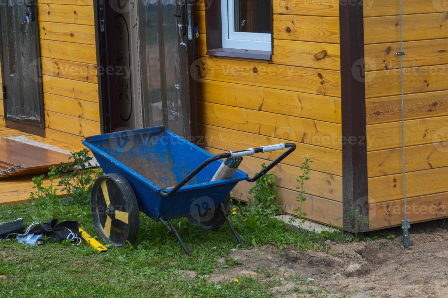 Construction industrial two-wheeled cart, wheelchair, tool stands on the street near the house of a garage at a construction site photo