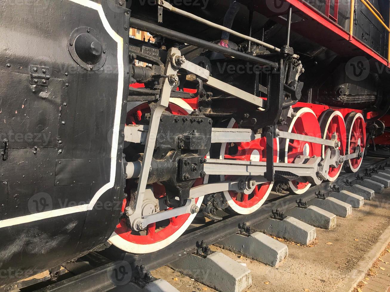 Large iron wheels of a red and black train standing on rails and suspension elements with springs of an old industrial steam locomotive photo