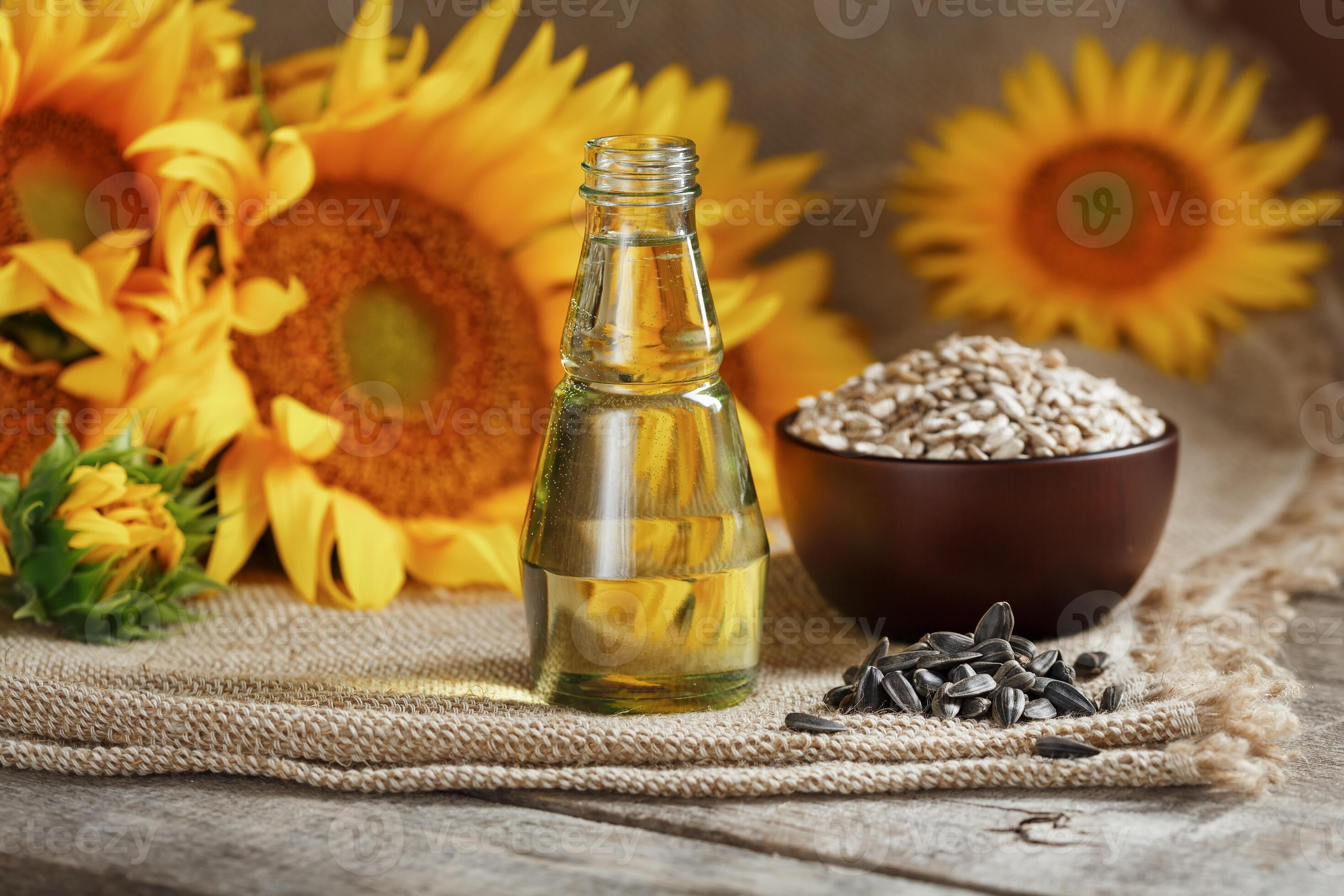 Sunflower oil in a glass bottle and flowers on a wooden background