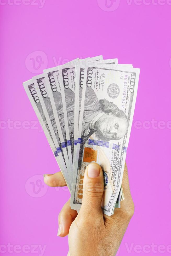 New dollar bills in hand on a pink background. The concept of financial assistance. photo