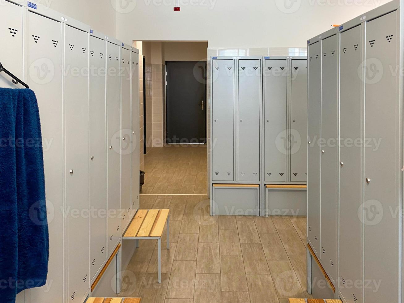 Metal lockers for clothes and benches in the locker room in the gym or at work at the enterprise for changing clothes for visitors or workers photo