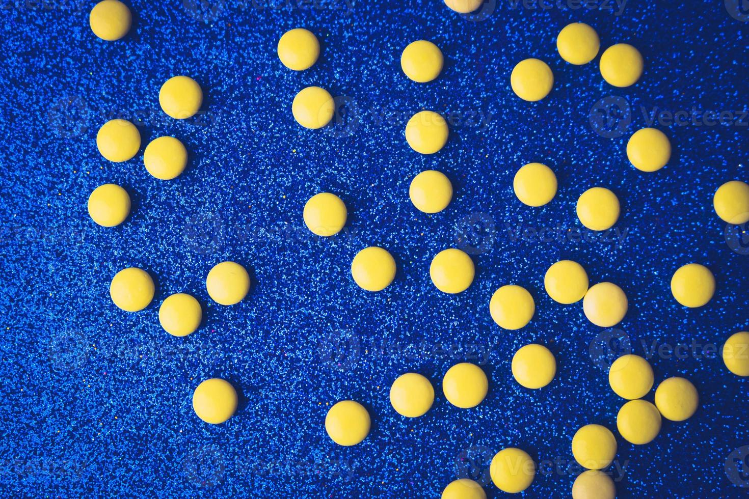 Small yellow orange beautiful medical pharmaceptic round pills, vitamins, drugs, antibiotics on a blue background, texture. Concept medicine, health care. Flat lay, top view photo