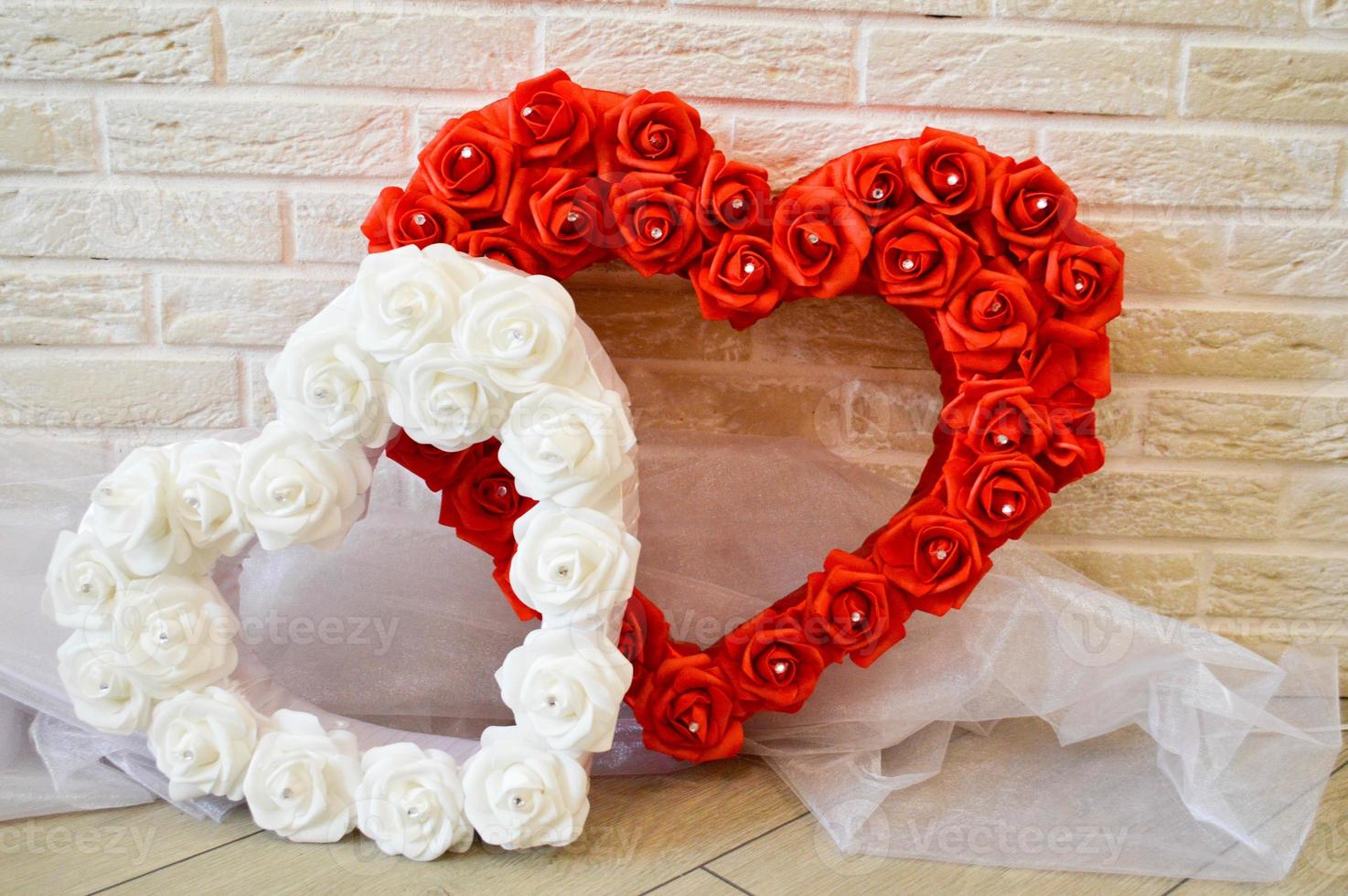 Two hearts. Red and white hearts with a pattern of roses with rhinestones against a brick wall. photo