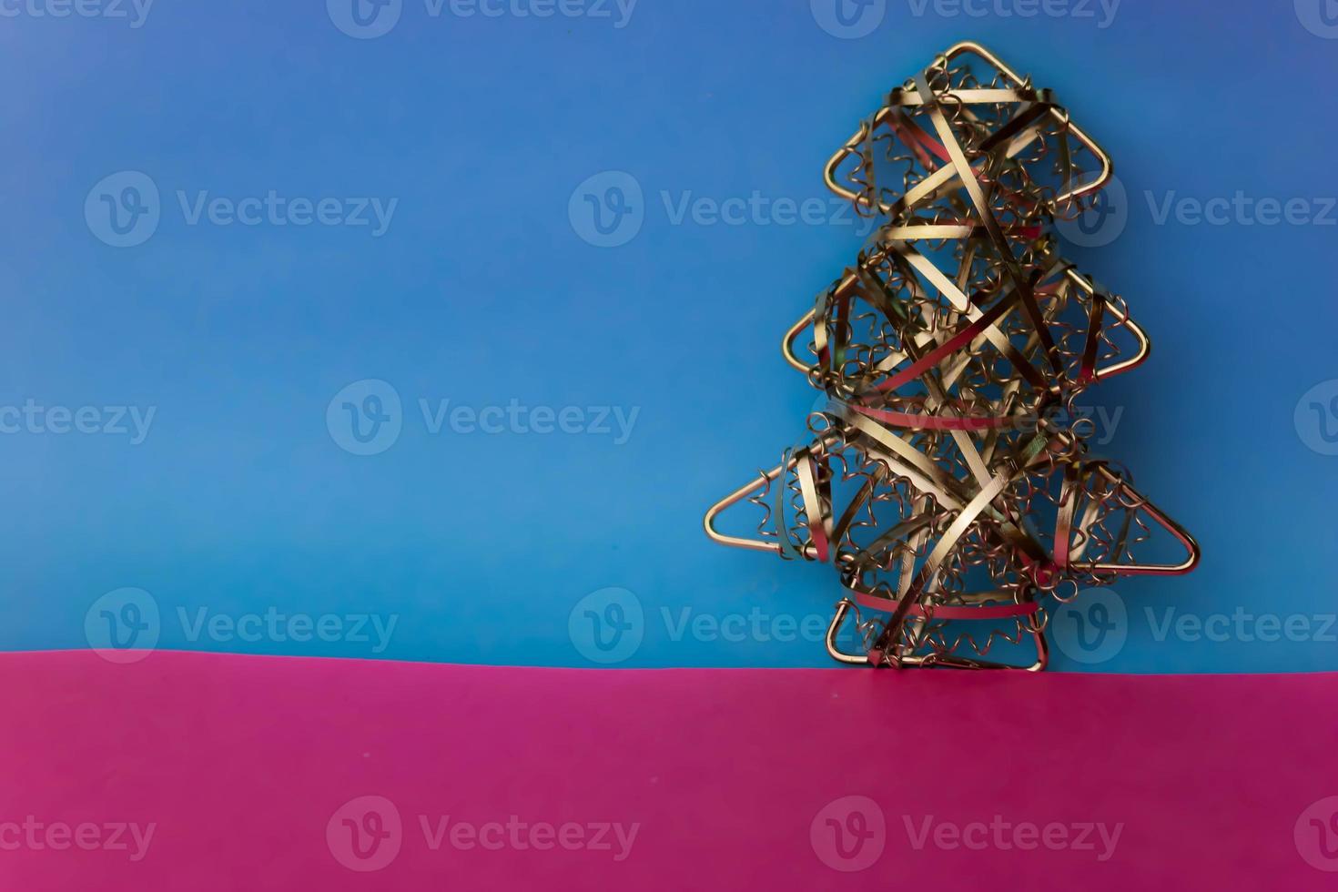 Festive Christmas Christmas happy blue-pink joyful background with a small toy metal iron golden homemade Christmas tree. Holiday decorations photo