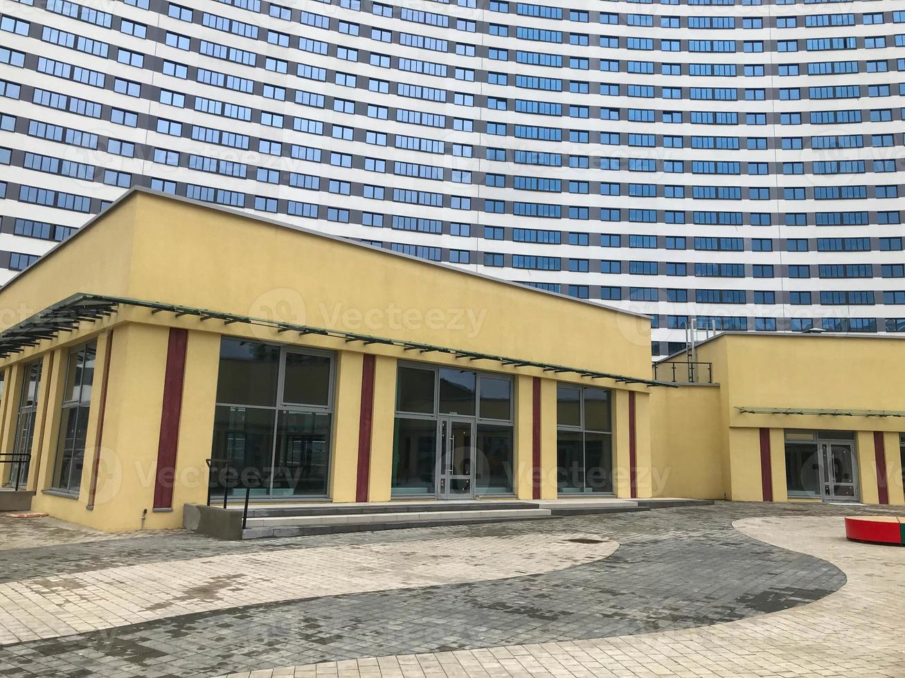 urban landscape, high-rise apartment buildings in blue and white. in the center there is a shopping complex in beige color, with windows for shopping. wide panoramic doors and windows for buyers photo