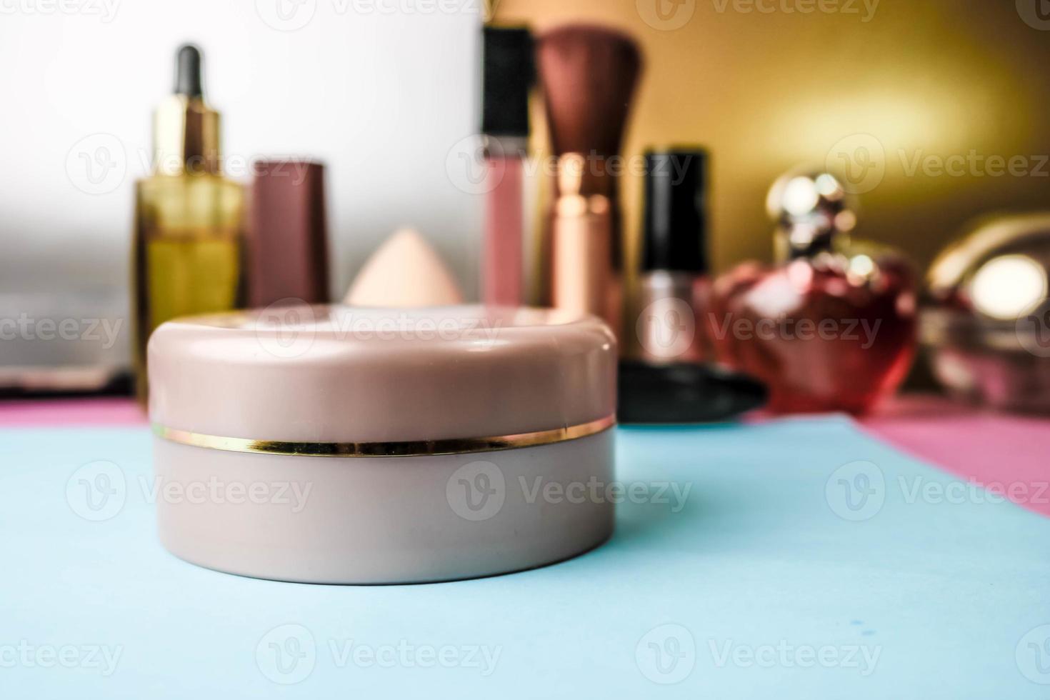 Pink round jar of cream, make-up base with the effect of a second skin on the background of a beauty makeup table photo