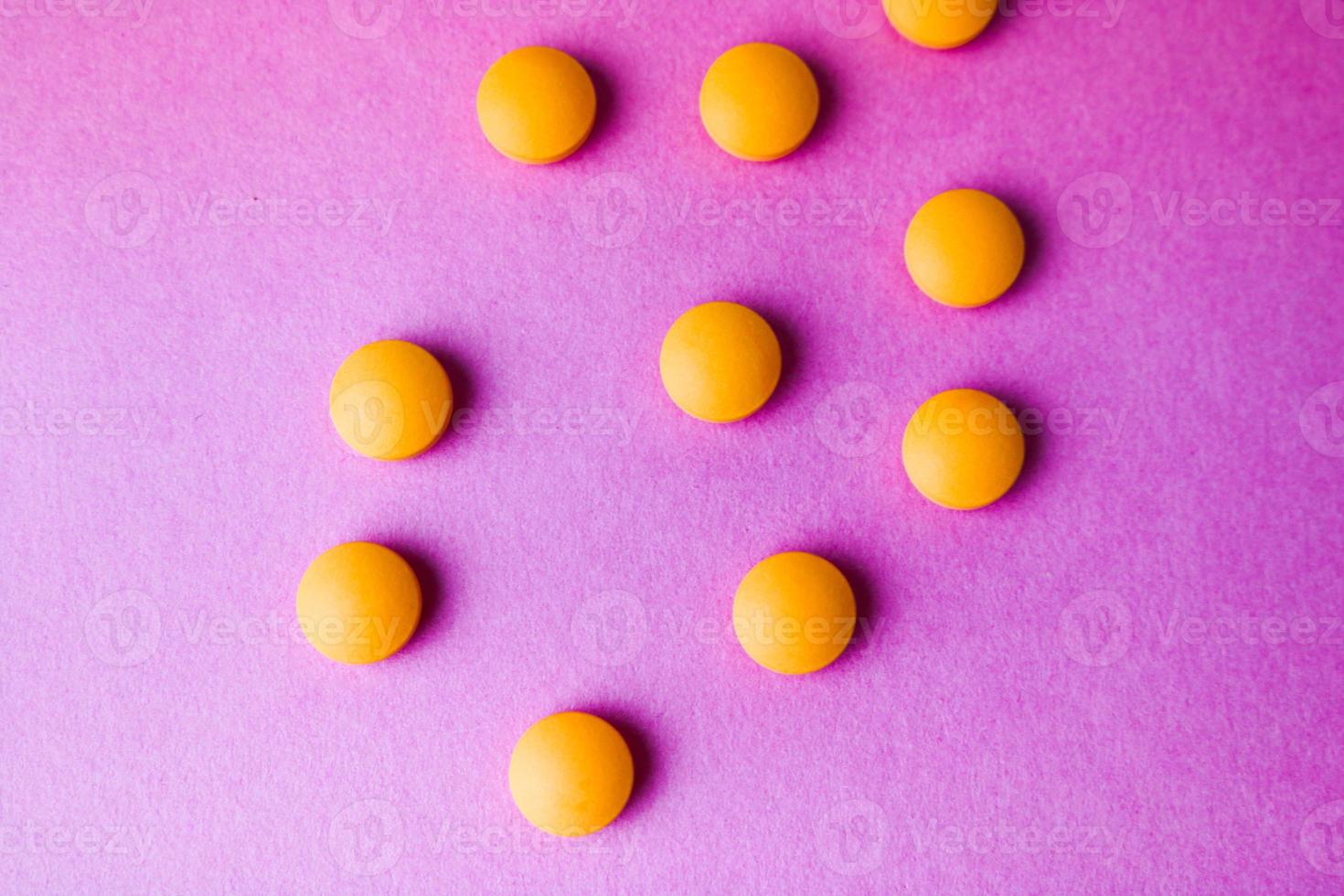 Small yellow orange beautiful medical pharmaceptic round pills, vitamins, drugs, antibiotics on a pink purple background, texture. Concept medicine, health care. Flat lay, top view photo