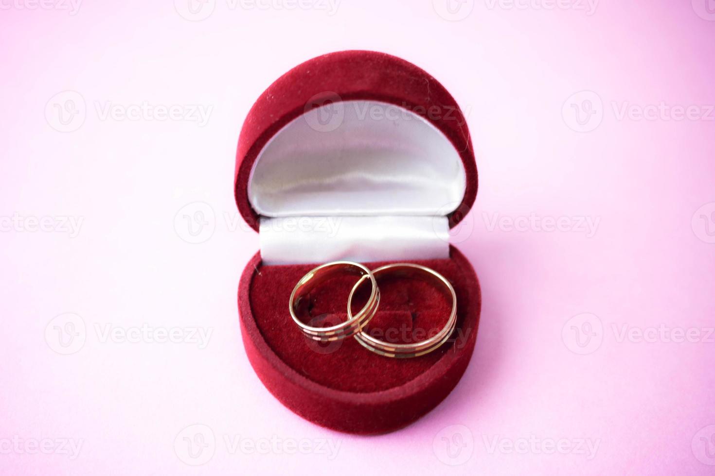 A beautiful red festive gift box velvet for two engagement, wedding rings with precious gold round precious pile rings. Concept marriage proposal, wedding, engagement photo