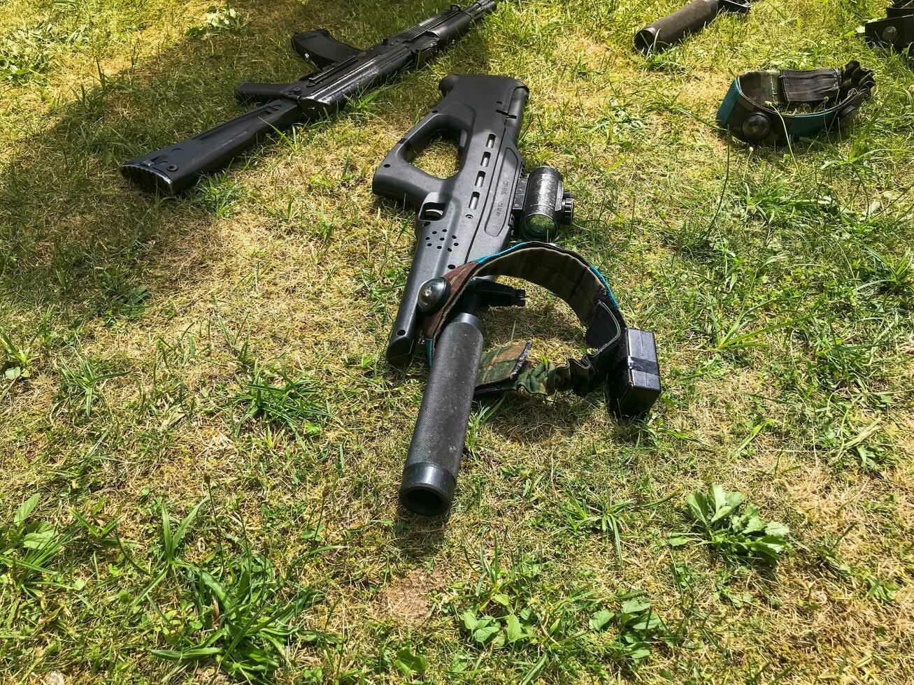 Black iron metal army military machine guns, small arms for soldiers with silencers lie on the background of green grass photo