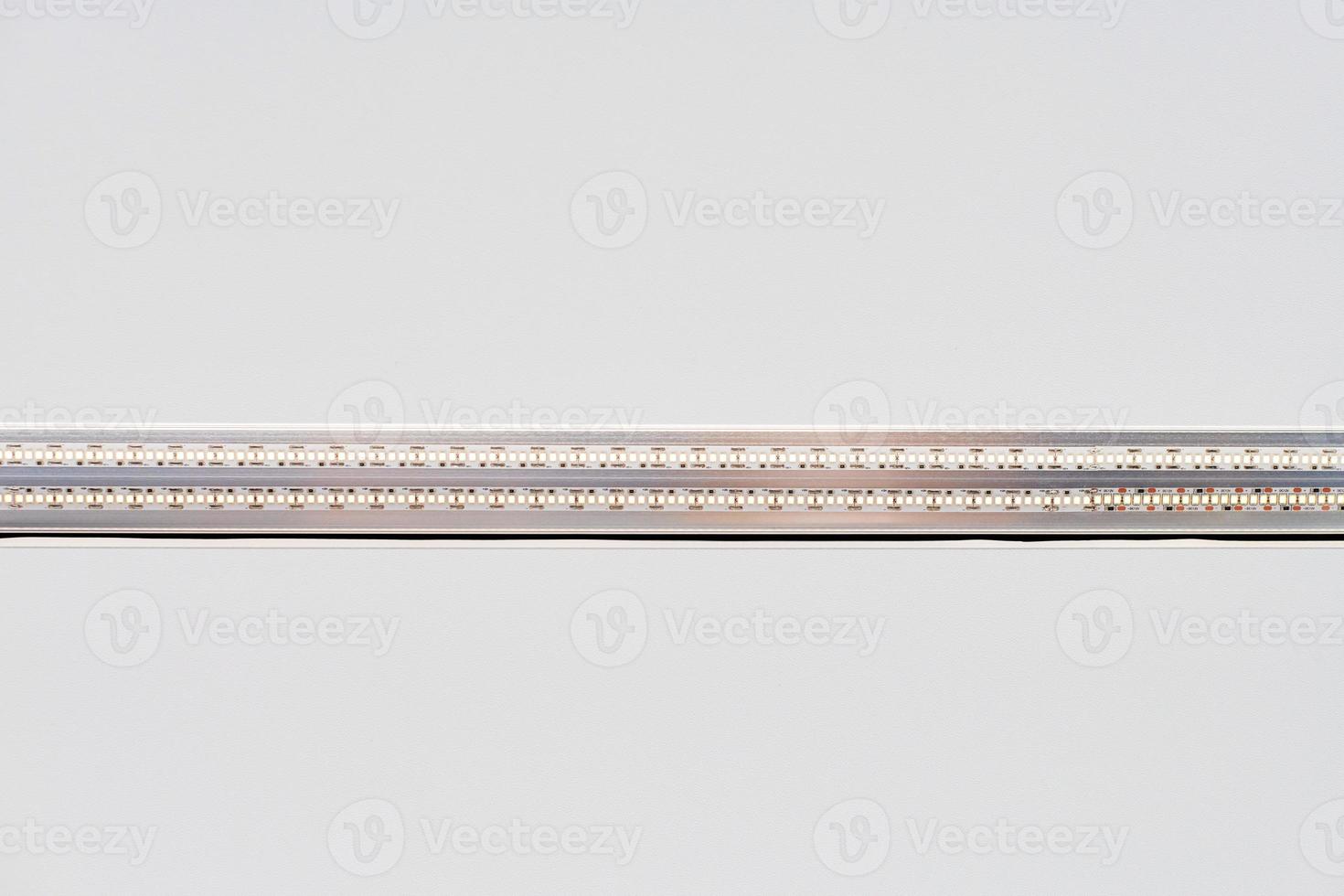 Strip LED light with aluminum profile on white stretch ceiling, modern construction, close up photo