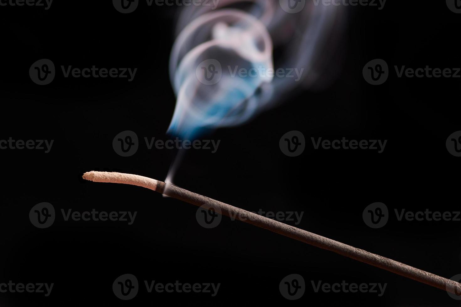 Smoke curls from burning incense stick for relaxation and meditation black background photo