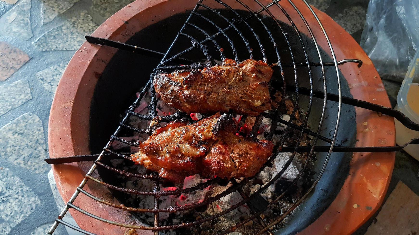 Two pieces of Grilled pork bone rib, beef or chicken charcoal stove. Barbeque in Thai style. Cooking Asian food to eat at camping time. Delicious meal and tasty photo