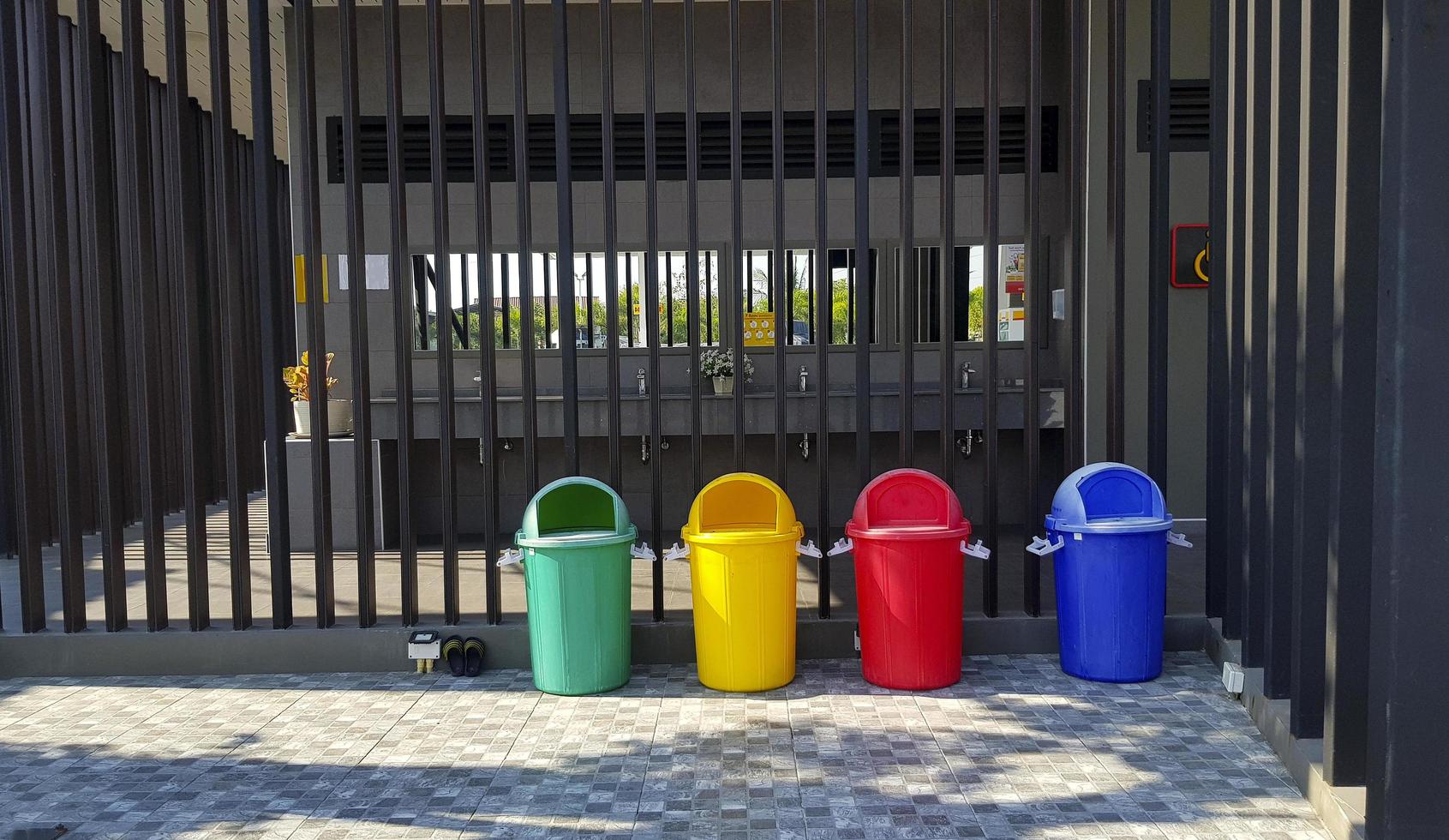 Many colorful recycle bin, dumping of garbage and child sandals putting in front of toilet, rest room or washroom with black stainless steel chrome or fence background. photo