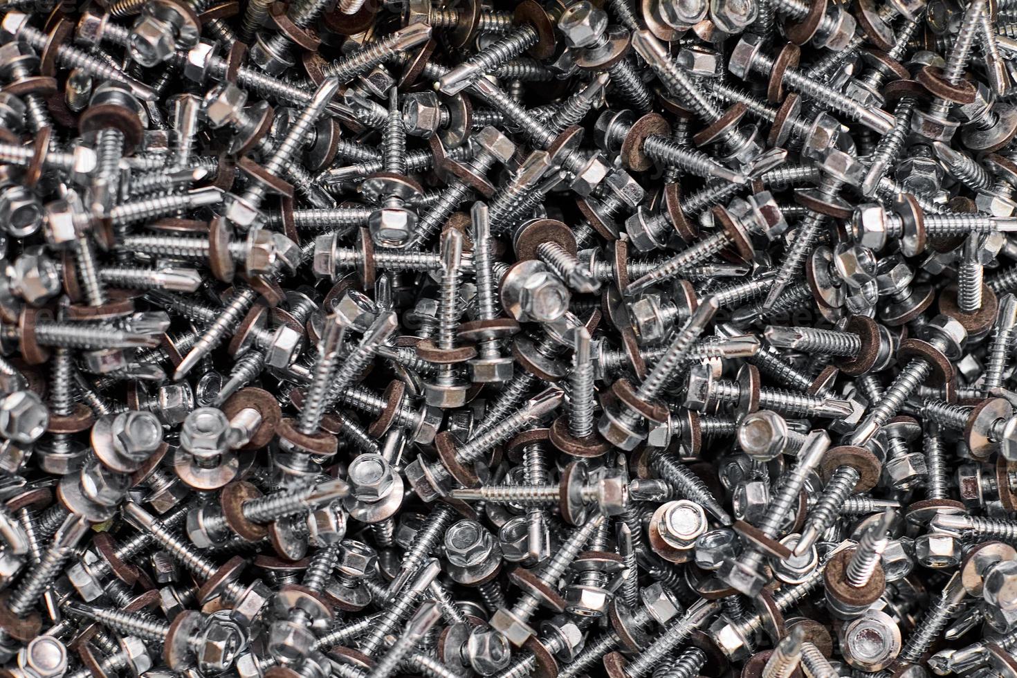 Bunch of galvanized self-drilling screws with washer and hexagonal head, hardware background photo