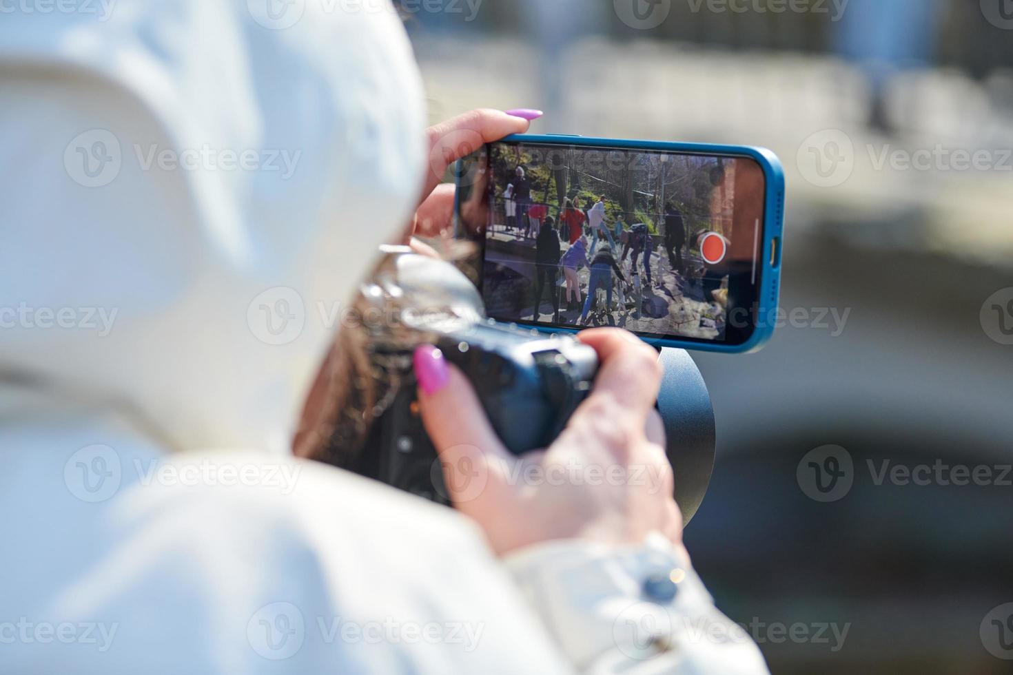 Woman videographer filming on DSLR camera and smartphone outdoor event, video photo blogging