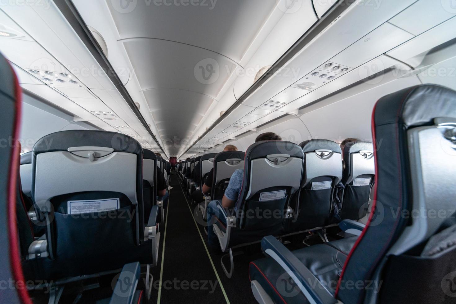 Airplane cabin seats with passengers. Economy class of new cheapest low-cost airlines. Travel trip to another country. Turbulence in flight. photo