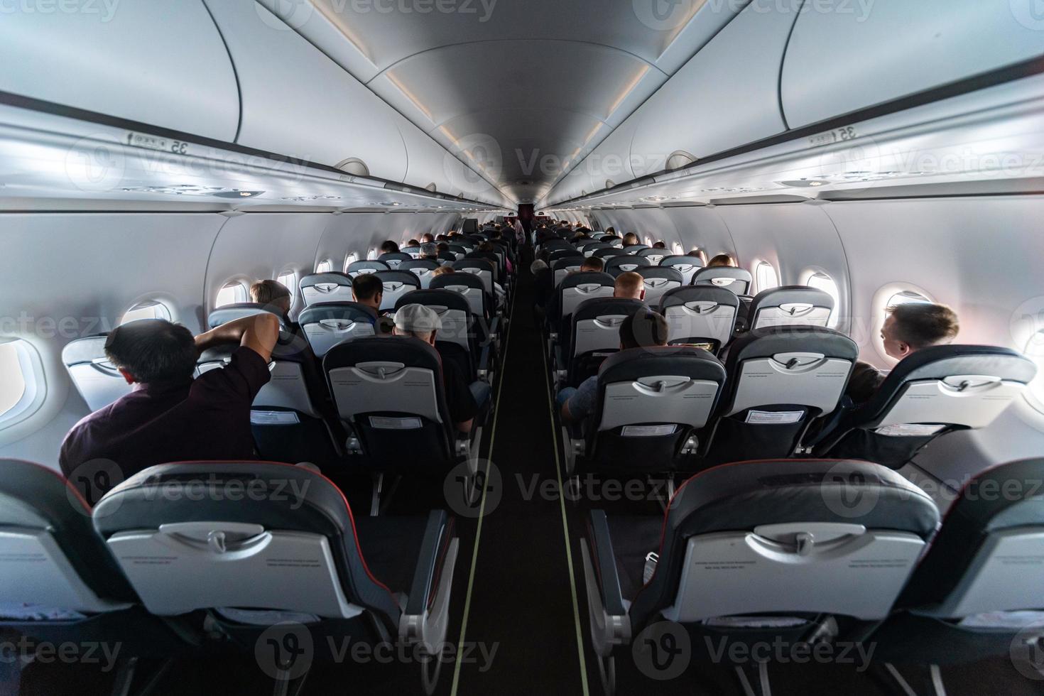 Airplane cabin seats with passengers. Economy class of new cheapest low-cost airlines without delay or cancellation of flight. Travel trip to another country. photo