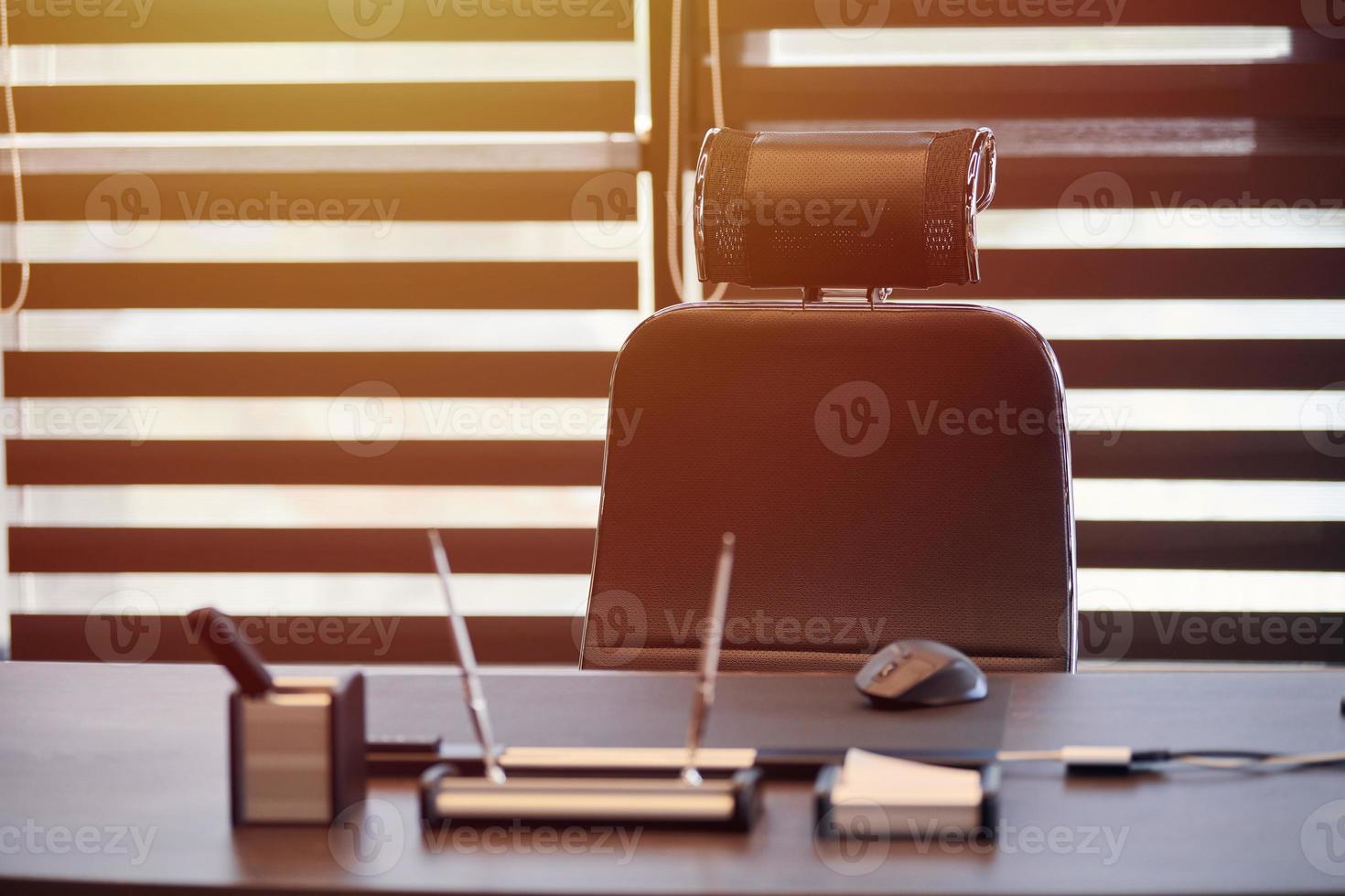 lugar de trabajo de la oficina de negocios. luz solar en el lugar de trabajo para jefe, jefe u otros empleados. mesa y silla cómoda. luz a través de las persianas entreabiertas foto