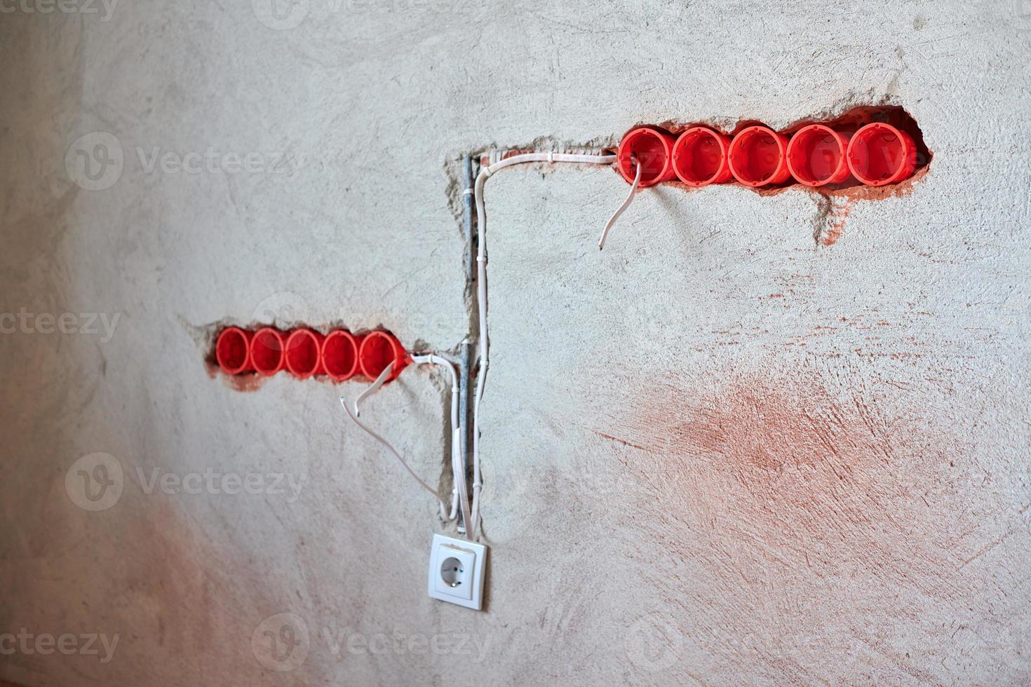 Plastic socket boxes and electrical wires on plastered wall photo
