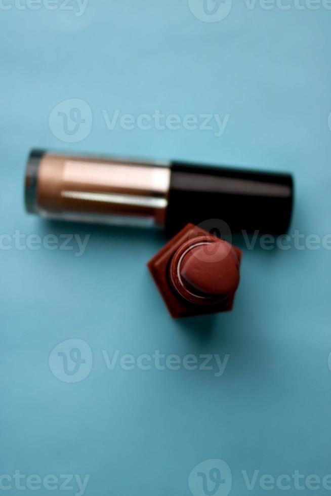 Beauty box, set of female cosmetics from the red lipstick and highlighter on a blue background. Flat lay. Top view photo