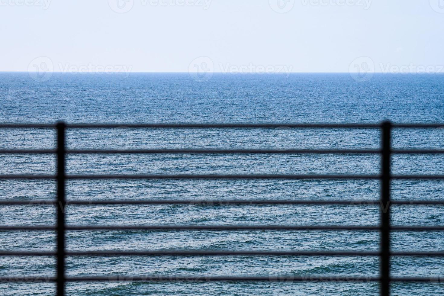 Fencing on observation deck, blue sea background, protection of tourists from falling off cliff photo