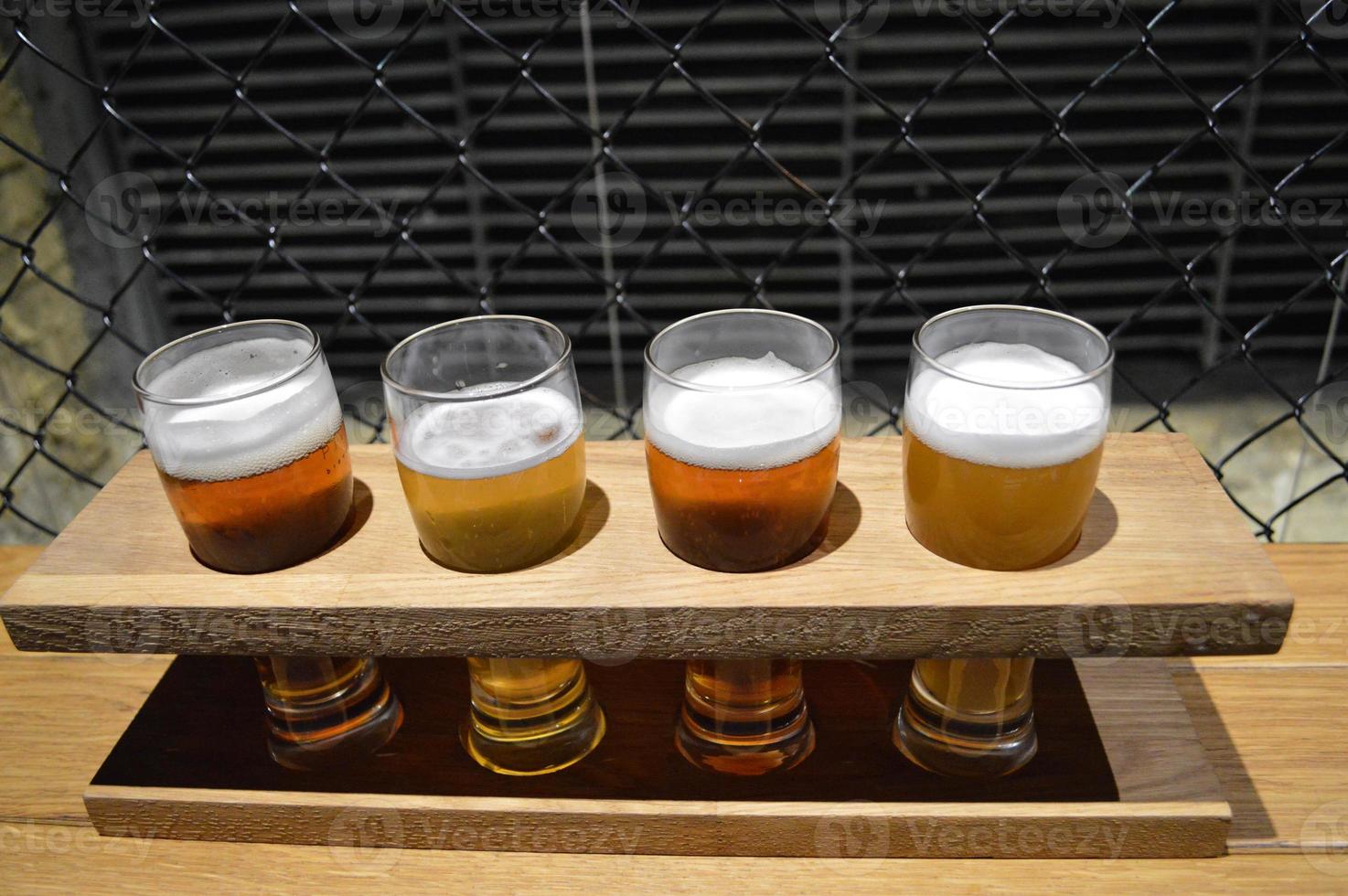 four glasses of beer in a wooden stand photo