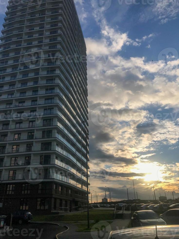 alto bloque residencial de pisos, columna en el centro de la ciudad. casa de nuevo formato, blanca, sin balcón con terraza acristalada y muchas ventanas. contra el fondo de un cielo soleado y brillante foto