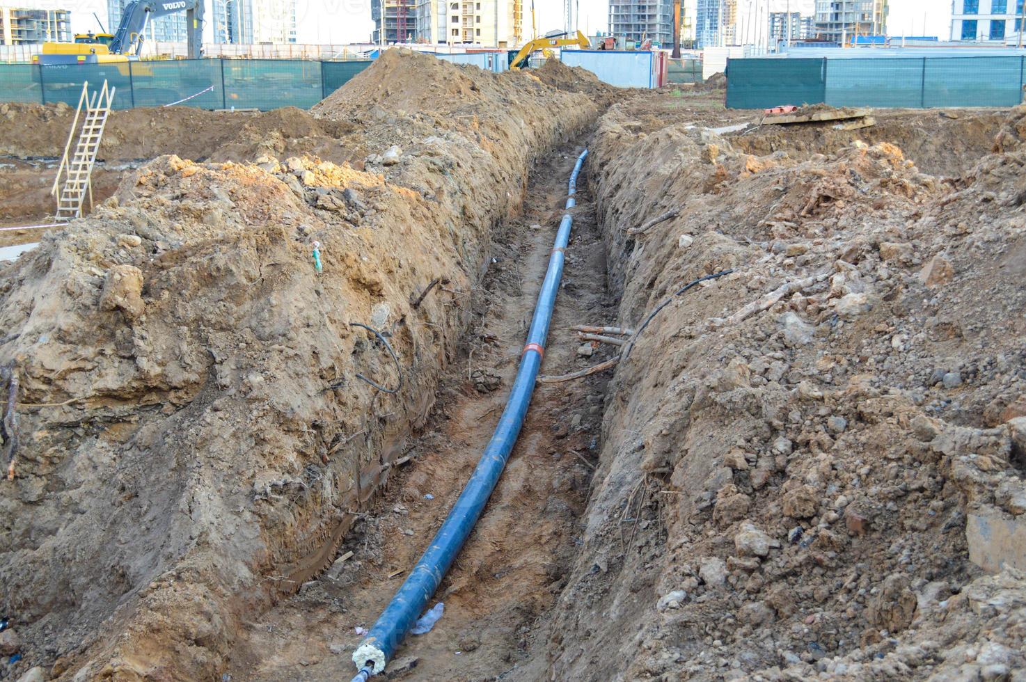 construction of underground communications. production of water runoff, sewerage system for waste disposal of a multi-storey building. the blue hard cable is buried underground photo