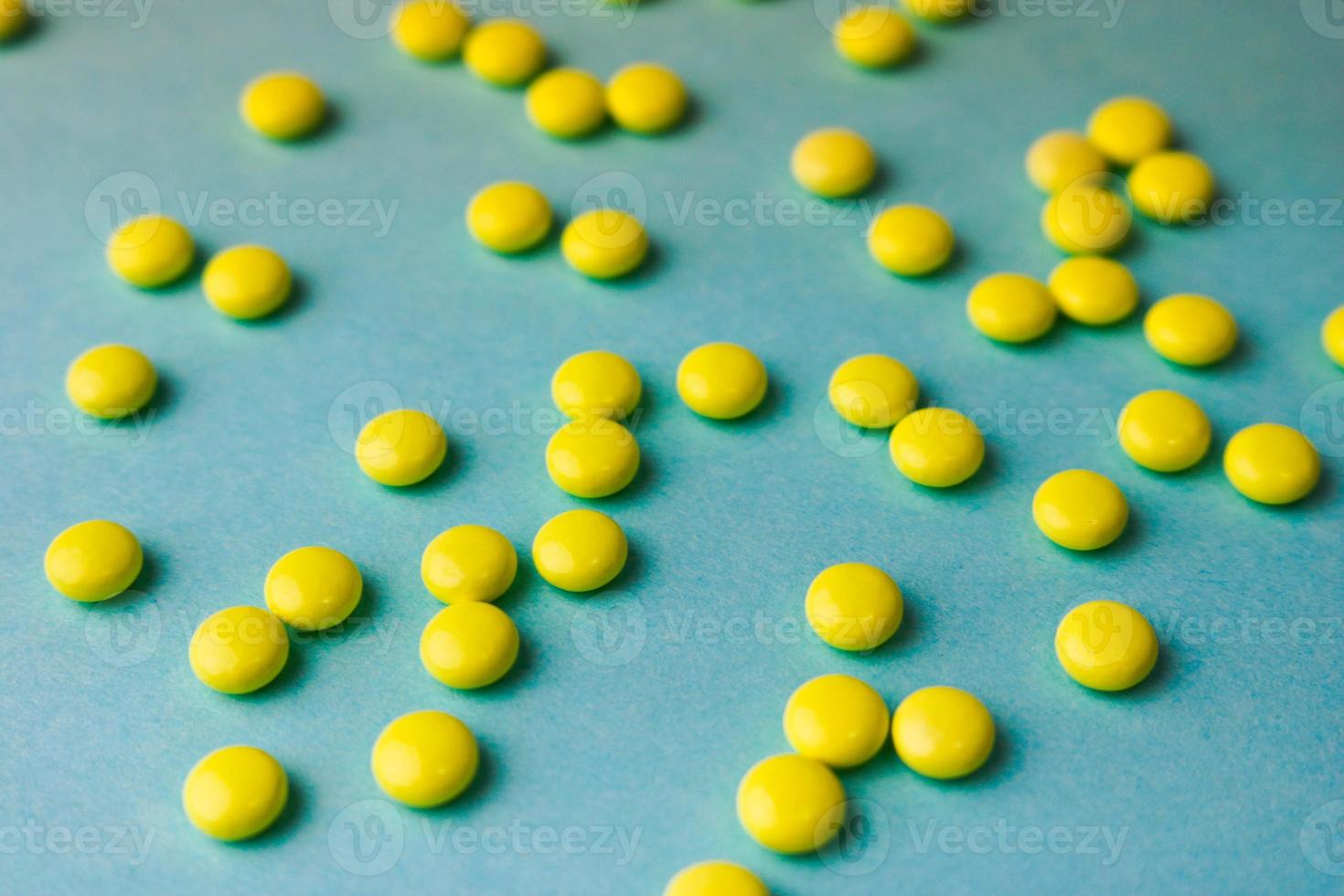 Small yellow orange beautiful medical pharmaceptic round pills, vitamins, drugs, antibiotics on a blue background, texture. Concept medicine, health care. Flat lay, top view photo