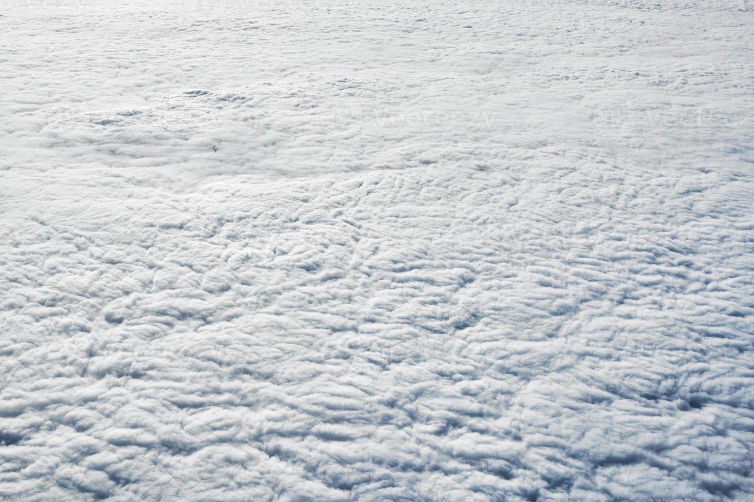 Over clouds top view from aircraft window, thick white blue clouds looks like soft foam photo