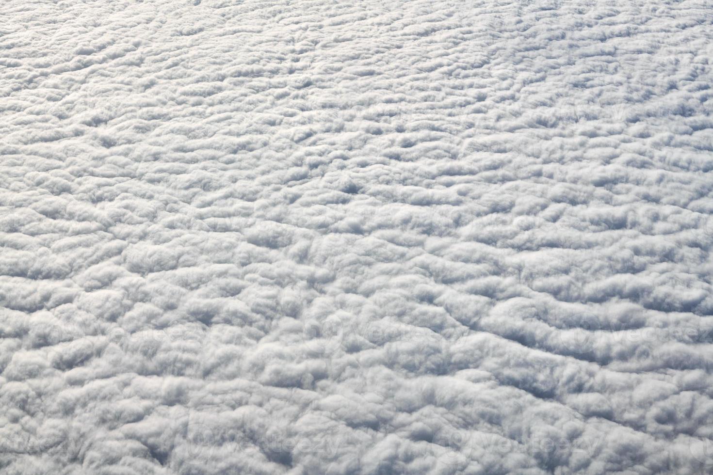 Breathtaking over clouds view from aircraft window, thick white blue clouds looks like soft foam photo