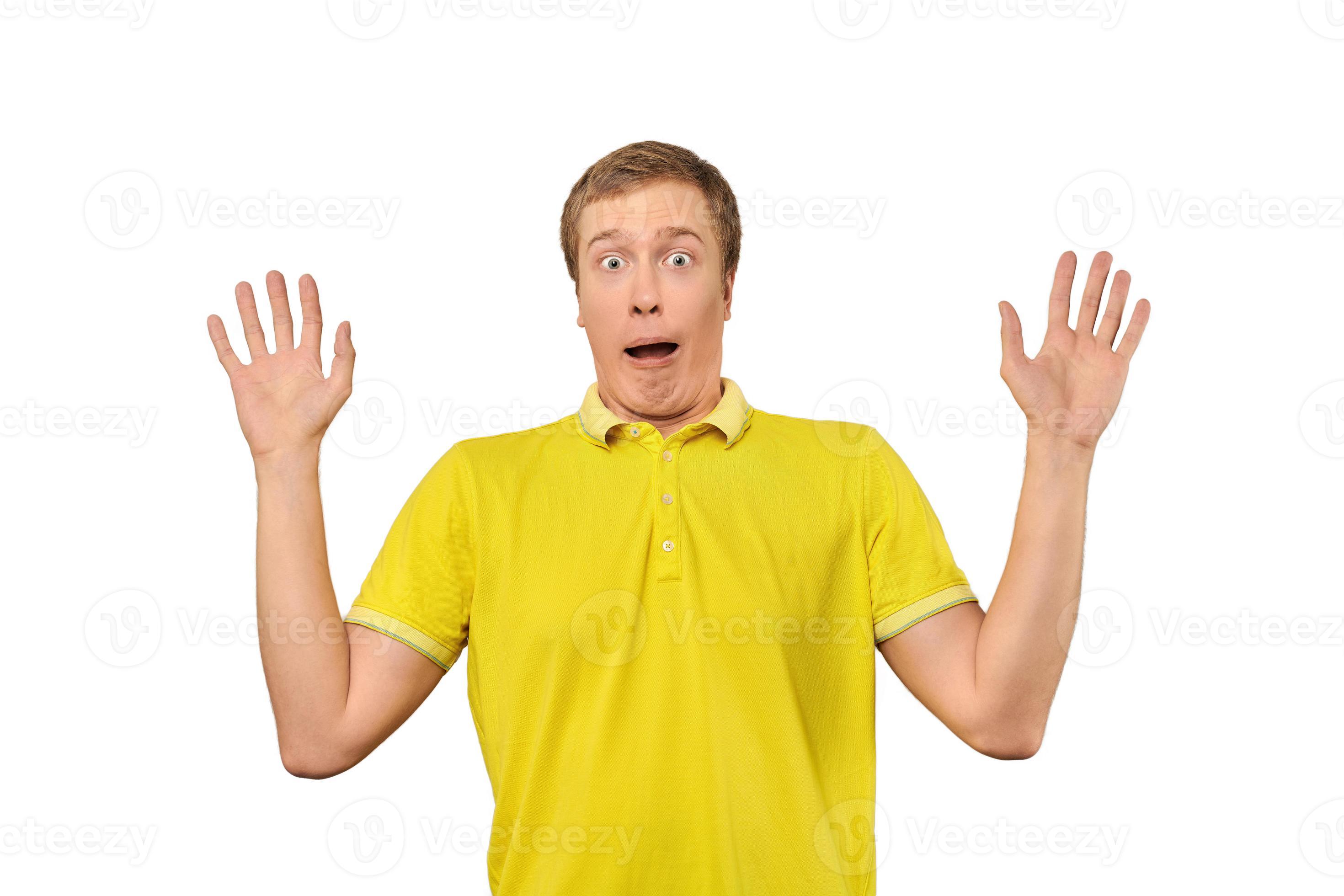 Scared young man with hands up in yellow Polo T shirt, white isolated