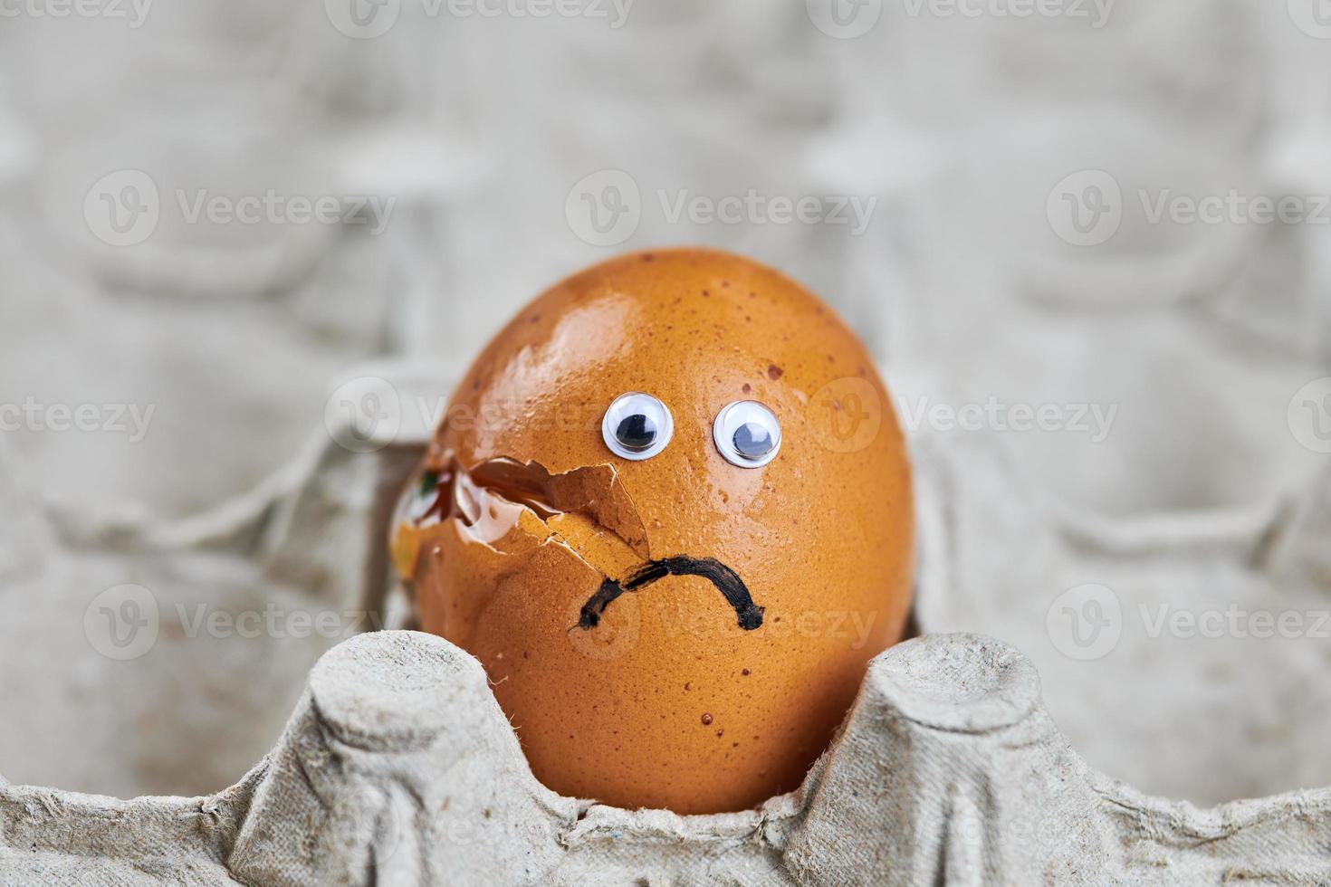 Sad cracked egg in paper egg tray photo