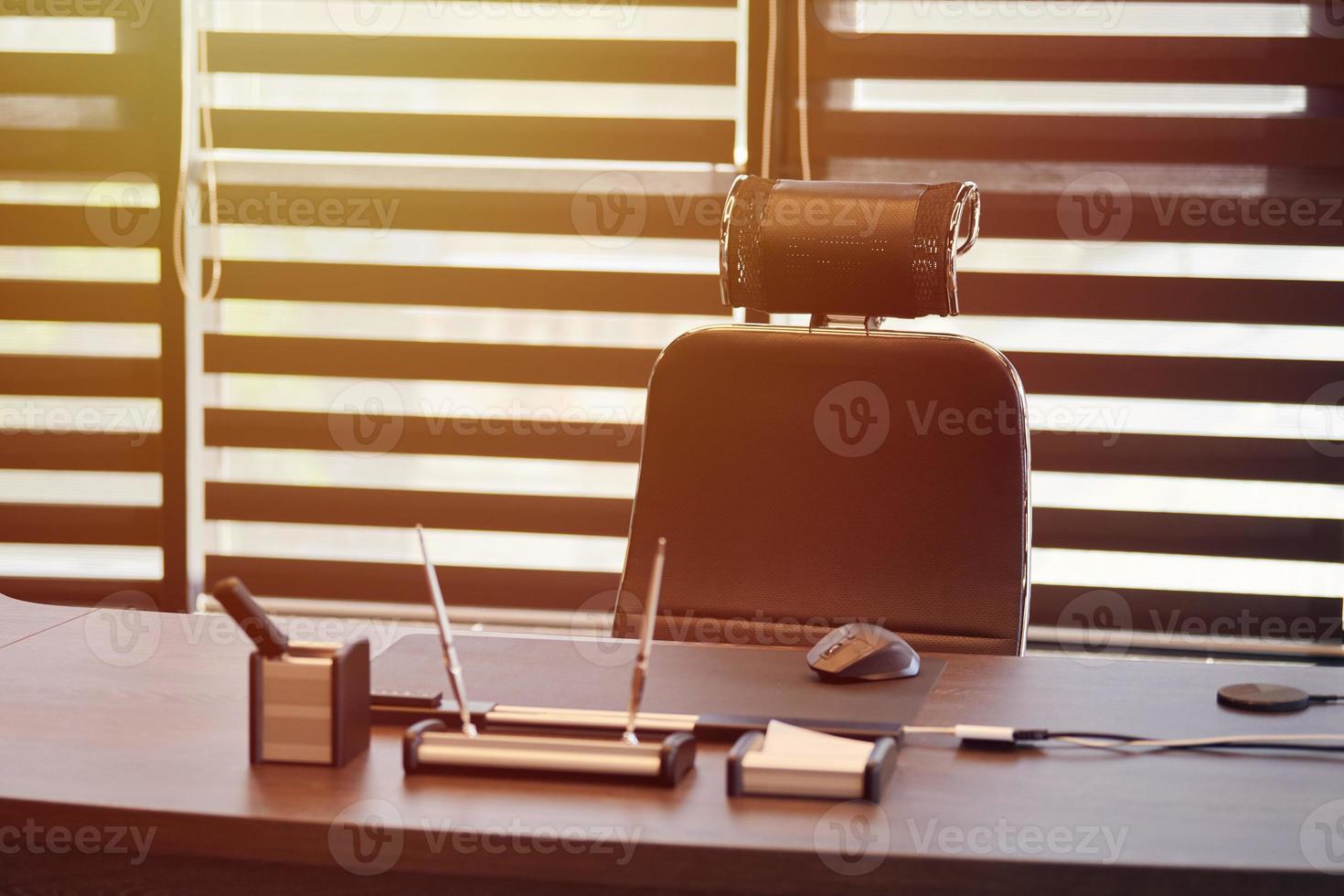 Business office workplace. Sunlight at work place for chief, boss or other employees. Table and comfortable chair. Light through the half open blinds photo