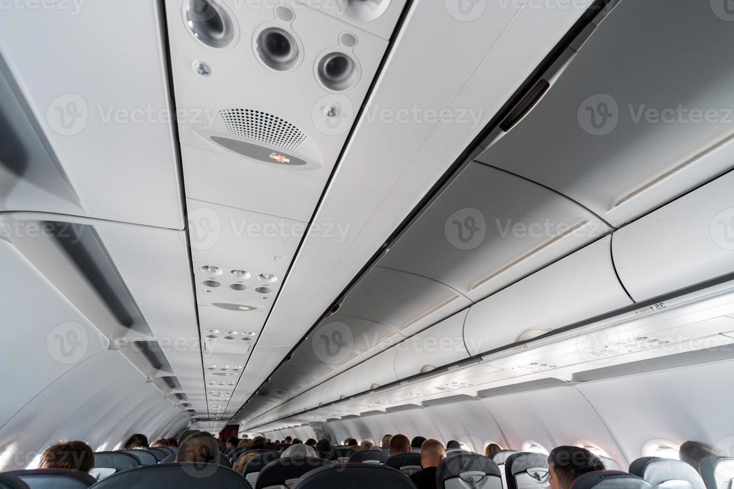 panel de control del aire acondicionado del avión sobre los asientos. aire viciado en la cabina del avión con gente. nueva aerolínea de bajo costo foto