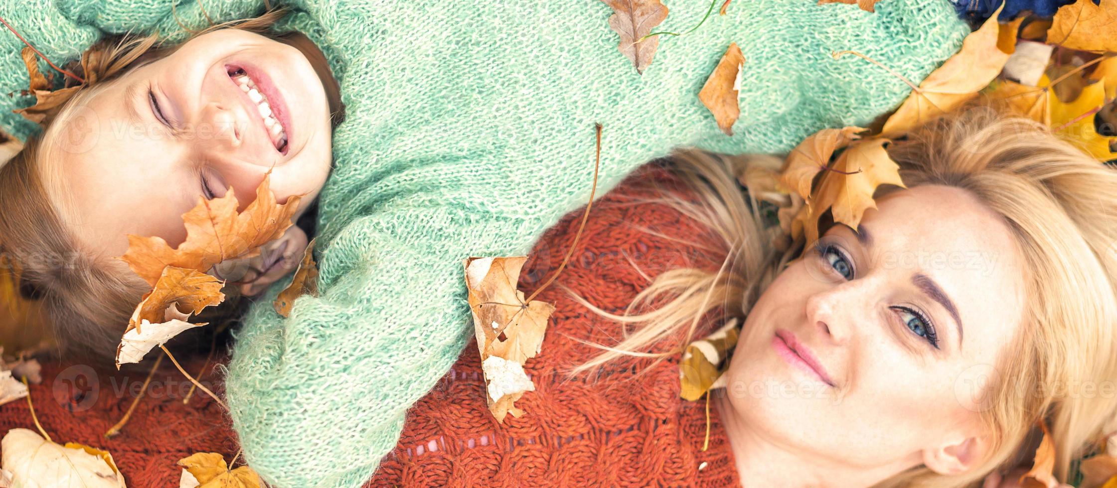 niña y mamá acostadas en hojas de otoño foto