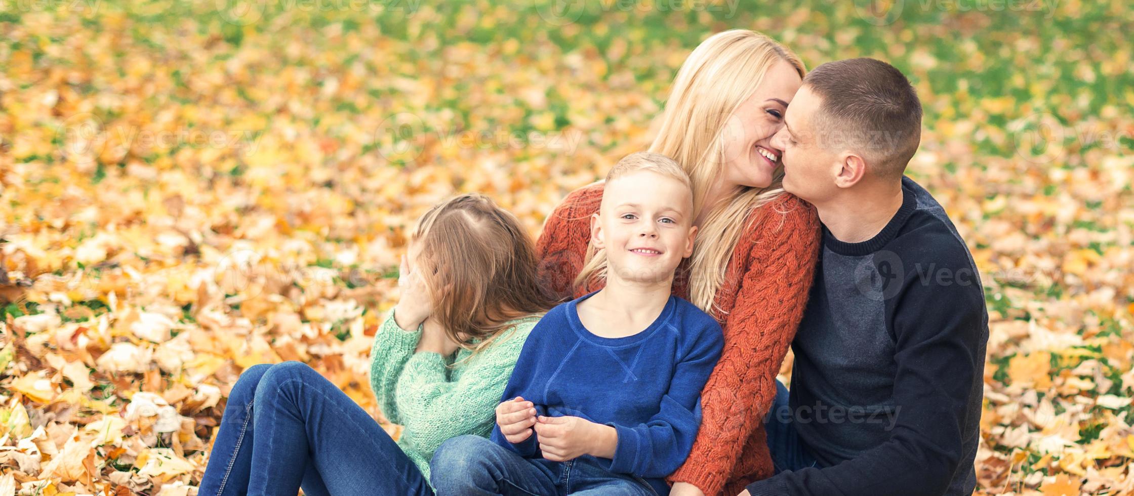 Portrait of young family sitting in autumn leaves photo