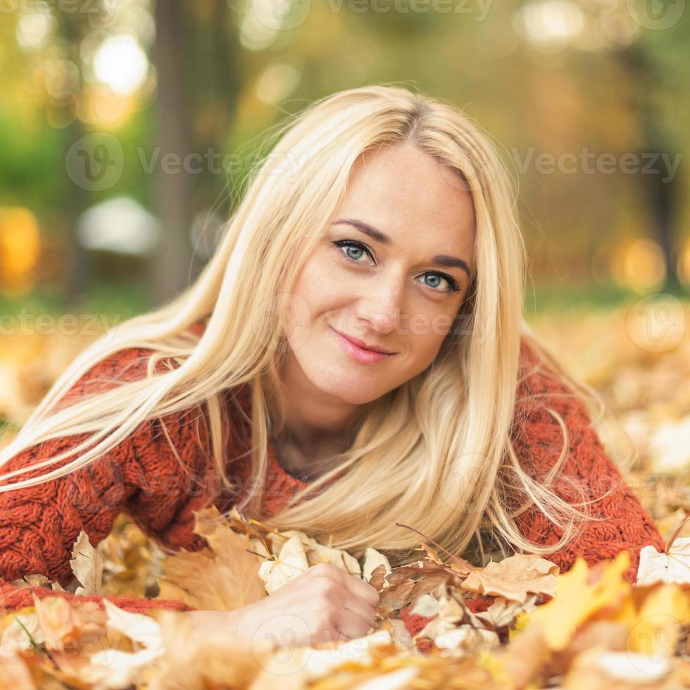Woman lies down on leaves at the autumn park photo