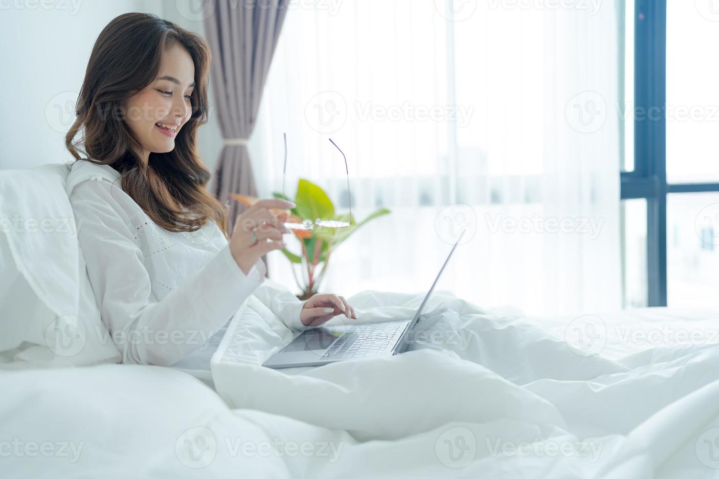 niña acostada en la cama jugando portátil en el dormitorio foto