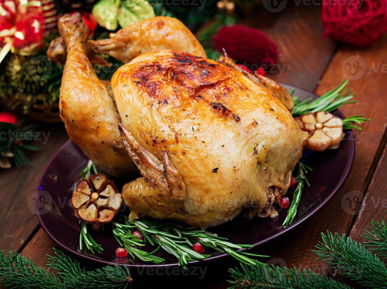 Baked turkey or chicken. The Christmas table is served with a turkey, decorated with bright tinsel and candles. Fried chicken, table. Christmas dinner. photo