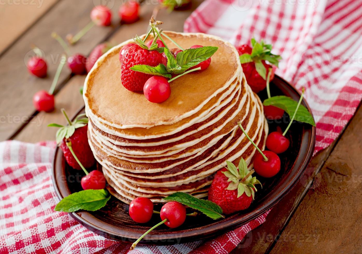 Pancakes with berries and syrup in a rustic style photo