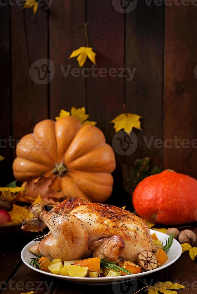 pavo asado adornado con arándanos sobre una mesa de estilo rústico decorada con calabazas, naranjas, manzanas y hojas de otoño. día de Gracias. foto