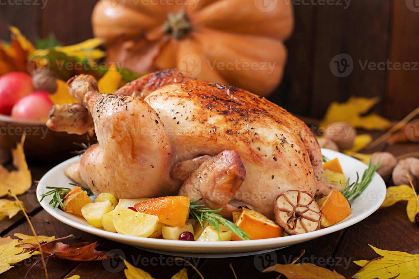 pavo asado adornado con arándanos sobre una mesa de estilo rústico decorada con calabazas, naranjas, manzanas y hojas de otoño. día de Gracias. foto