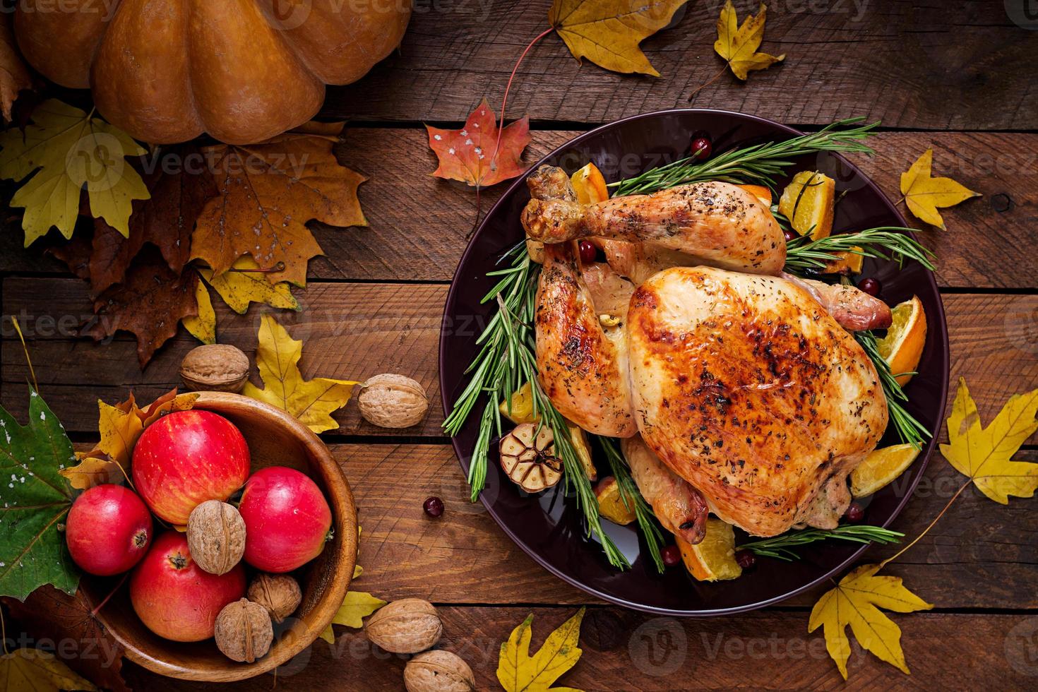 Roasted turkey garnished with cranberries on a rustic style table decorated with pumpkins, orange, apples and autumn leaf. Thanksgiving Day. Flat lay. Top view photo