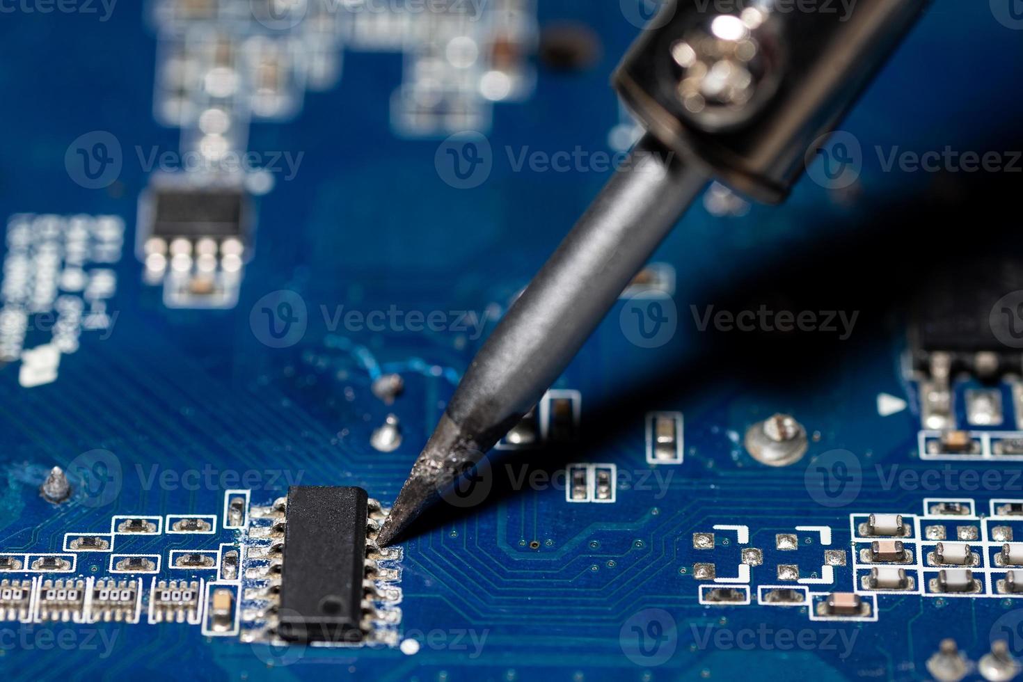 Repairman is soldering the motherboard of electronic device. photo
