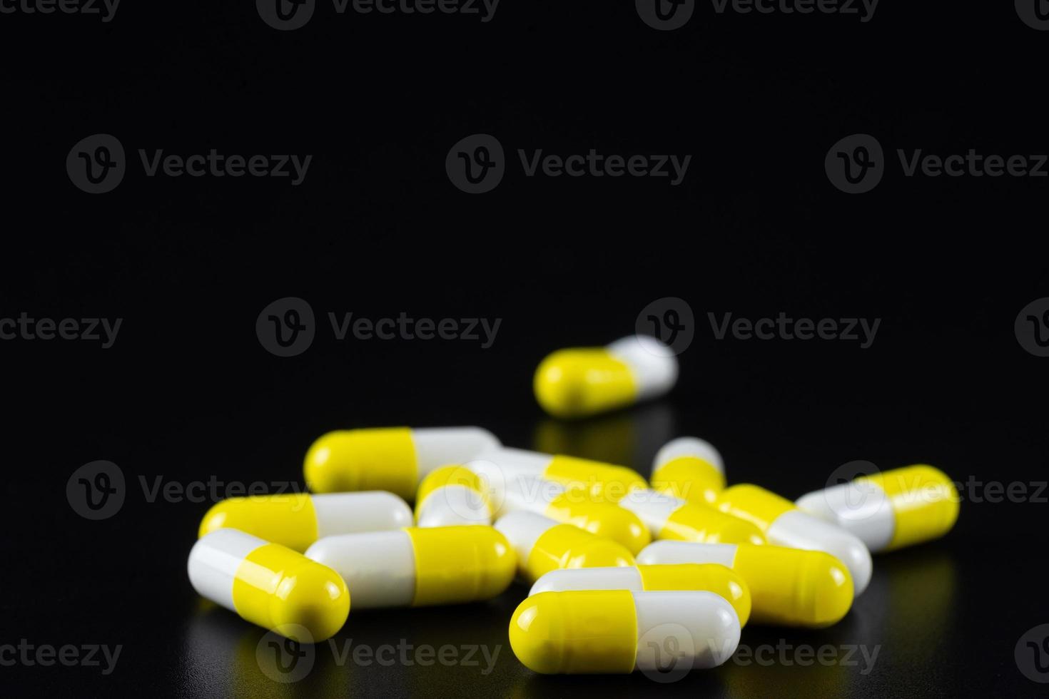 White tablet with two pills in background. Black background with reflection. photo