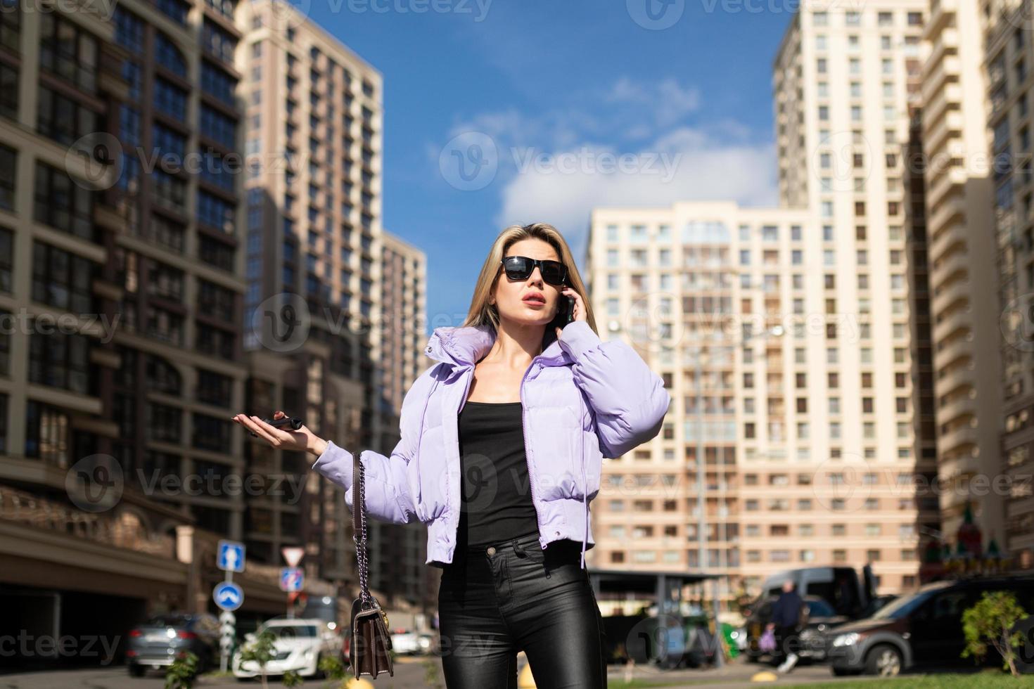 a young woman against the backdrop of an urban sleeping quarter speaks on a mobile phone, cannot find an address photo