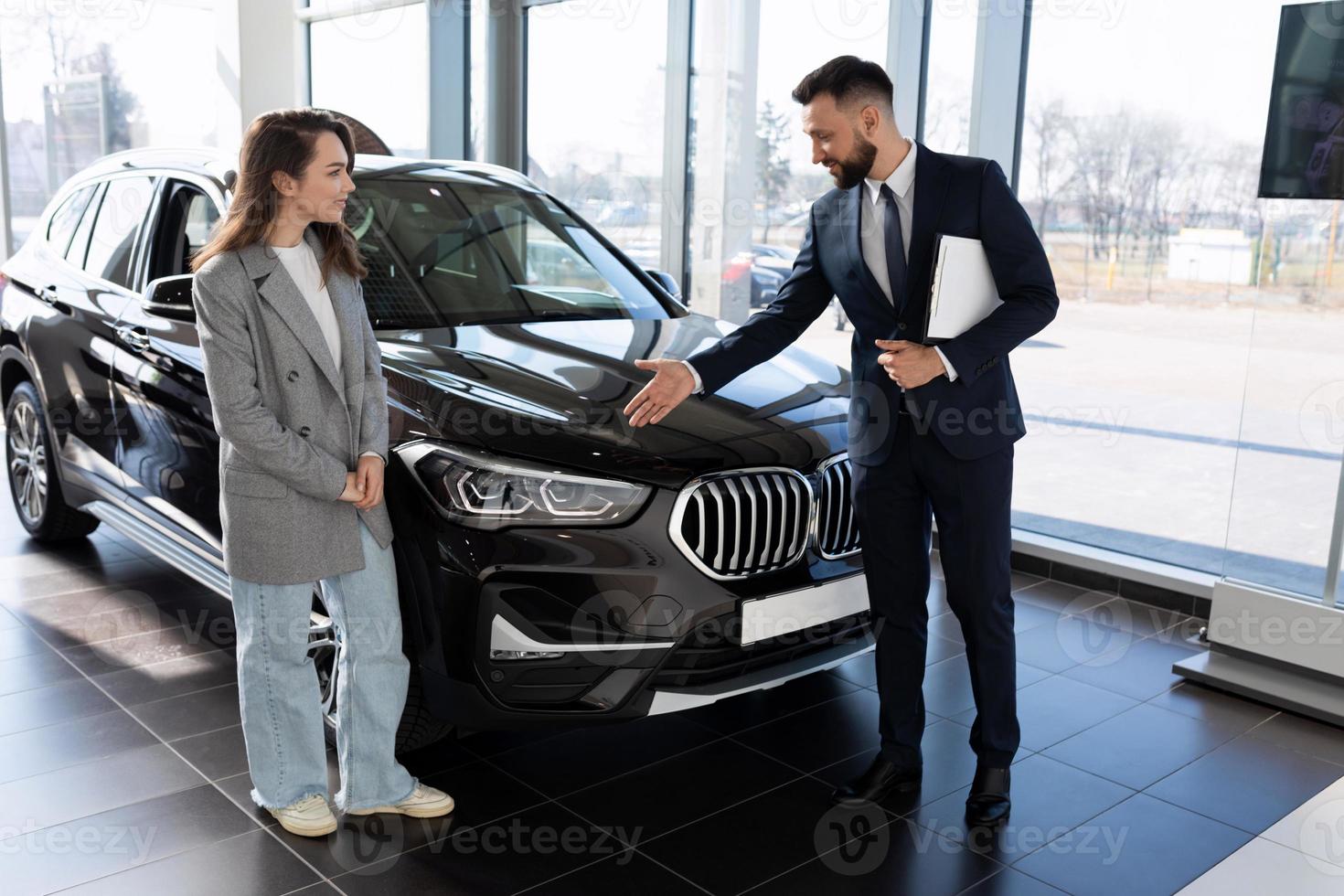 a representative of a car dealership demonstrates a car to a buyer